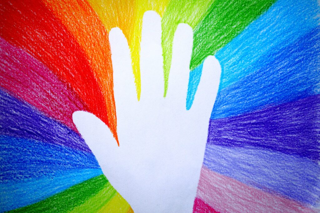 bright white silhouette of a hand drawn hand on top of a rainbow wheel background